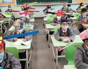 Crianças usam chapéus com ‘hélices’ para manter distância em escola